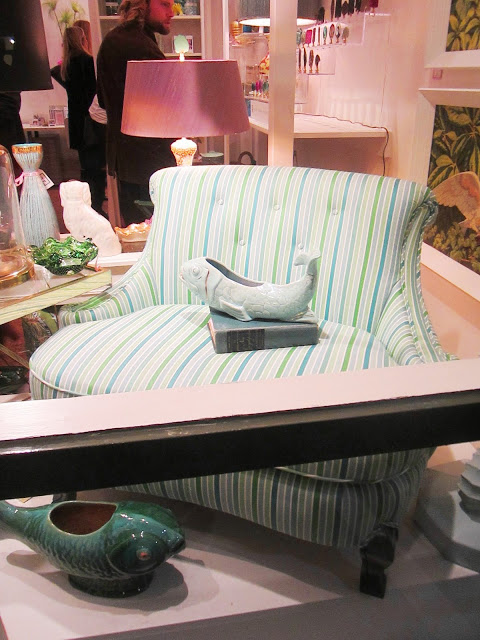 colorful blue, green and white striped settee in the window with a ceramic fish dish