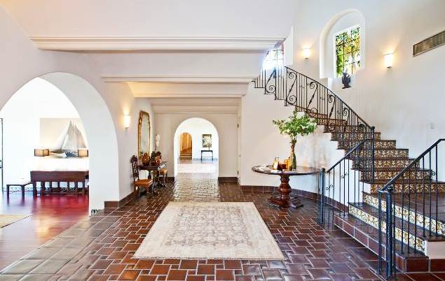 foyer with glazed Saltillo tile floor and stairs with arched entryways into other rooms