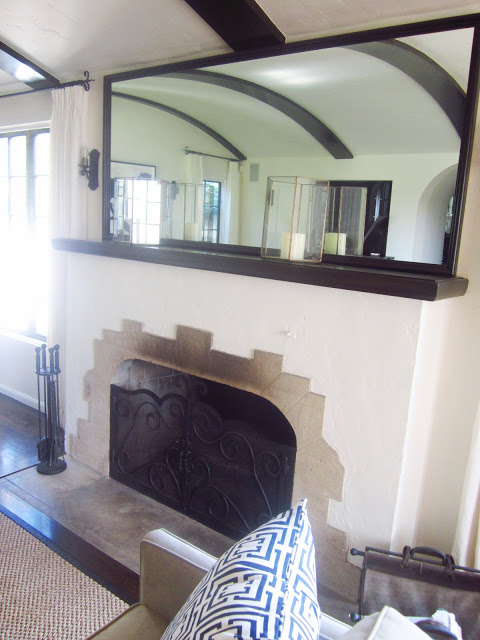 fireplace with Batchelder tiles with two candles and a large mirror on the mantel
