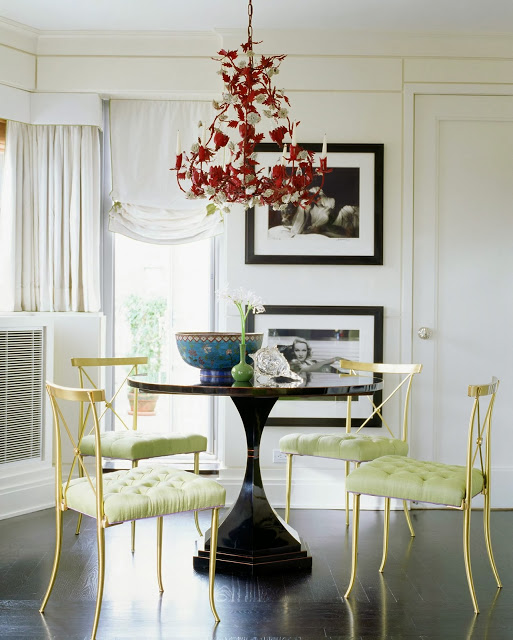 Dining room with gold chairs with mint green tufted seat cushions and a red chandelier