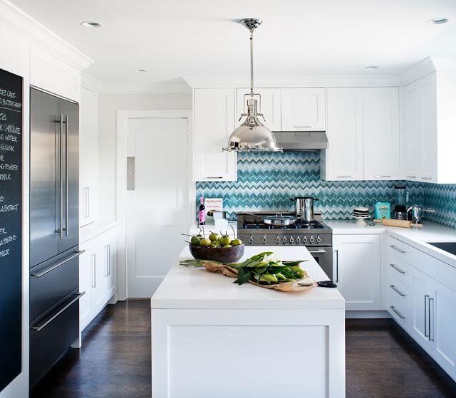 kitchen with blue and white zig zag chevron tiles, white cabinets and center island, polished metal stove, french door refrigerators and a chalkboard wall by Jute