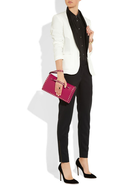 Model wearing black skinny pants, a white tuxedo jacket, black pumps and holding a pink Valentino Rockstud Clutch