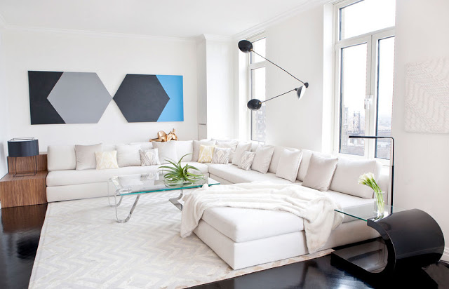 Living room with a large white sectional, glossy dark floor, glass coffee table and modern art