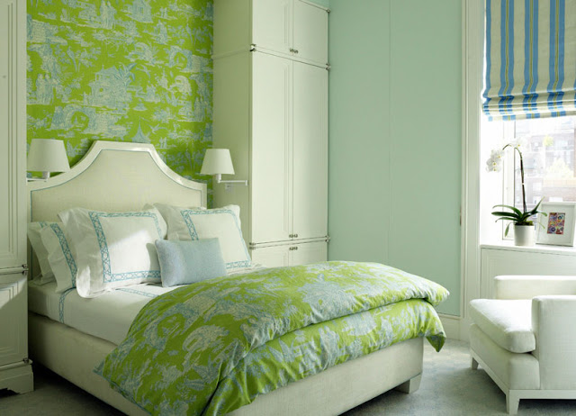 bedroom with wall covered in green toile wallpaper. The bed has a molded headboard and is surrounded by two wall sized wardobes