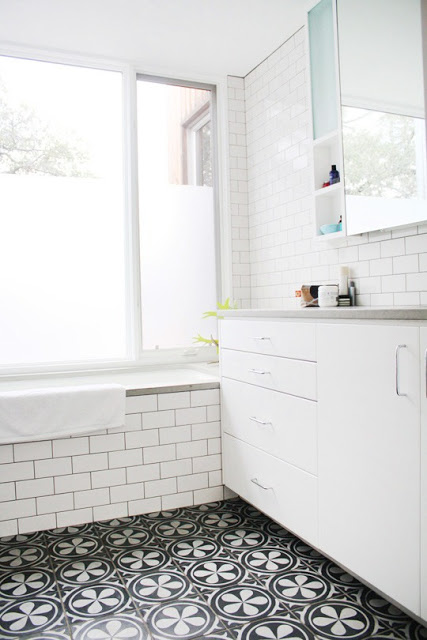 Bathroom with subway tile walls, floral mosaic tile floor, step in tub and white cabinets with chrome drawer pulls