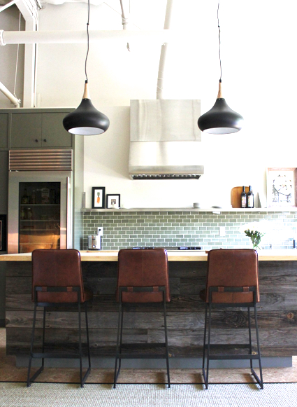 wine country home designed by Krista Schrock and David John Dick with reclaimed wood paneled kitchen island, black pendant lights, leather barstools and green subway tile backsplash