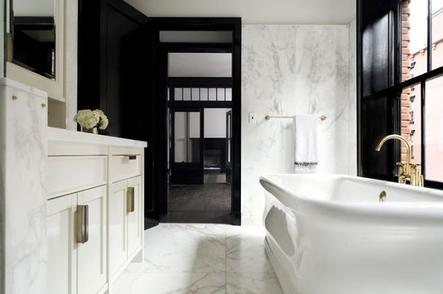 michael mundy's black and white bathroom with white freestanding tub, black lacquer trimed door,  glossy brass faucet pulls, and carrara marble floors, walls and counters 