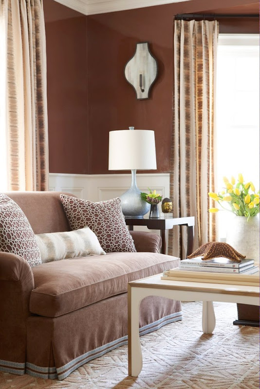 Family room with brown walls, a brown sofa with brown and white accent pillows and a light wood coffee table