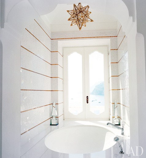 Glamorous gold and white striped bathroom with a step in tub with and a star pendant lamp