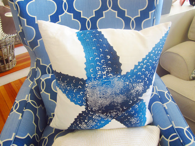 close up of white pillow with a blue starfish printed on it and the arm chair