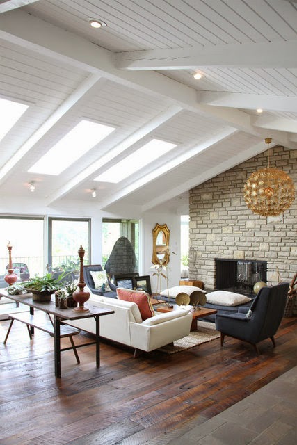 Living room with stone fireplace, skylights and rustic wood floor