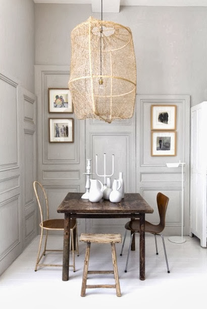Dining room with paneled walls in a tiny French apartment with mismatched Arne Jacobsen Series 7 chairs, reclaimed wood table and an oversized pendant light