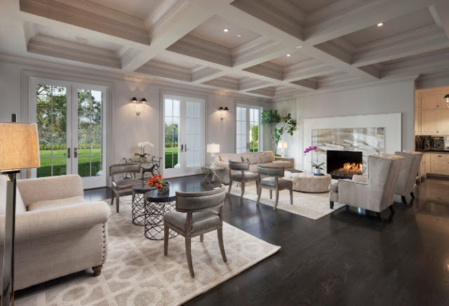 Living room mansion coffered ceiling wood floor marble fireplace mantel white armchairs with nail head trim white sofa French doors