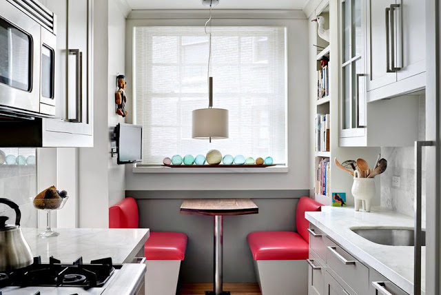 breakfast nook with red vinyl banquette bench seating and small galley kitchen with shaker cabinets, marble counter, and fisherman float balls in window