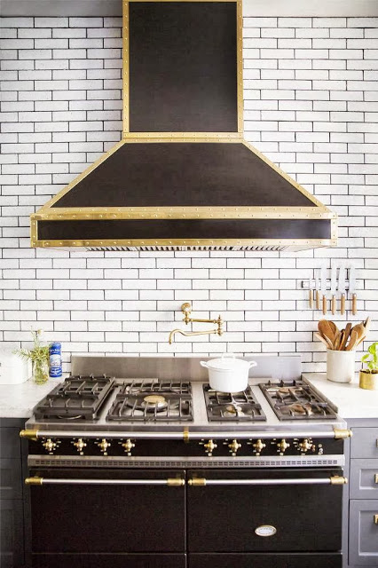 Kitchen in a New York City apartment with subway tile backsplash and a hood with brass accents