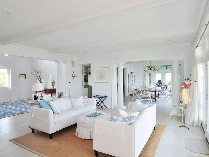 White living room with sea grass rug, dueling sofas, a white oval upholstered ottoman and a coffered ceiling
