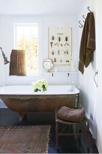 master bathroom with stand alone copper tub, dark wood floors, white walls, a small table used to hold towels, a window and poster with different insects 