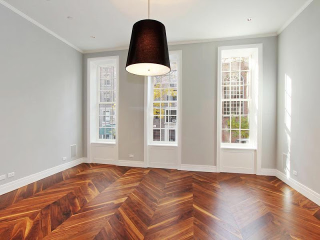 Living room with herringbone wood floor, black pendant light and tall encasement windows with white trim