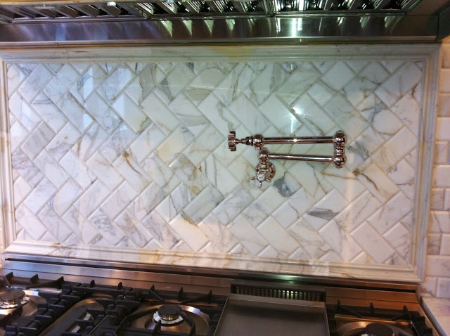 Kitchen with brushed nickel Rohl pot filler above the range is mounted on a Calacatta gold marble backsplash set in a herringbone pattern