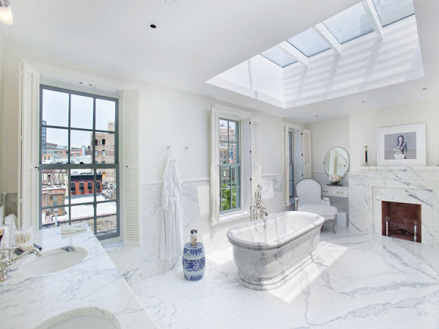 master bathroom with a marble bathtub and fireplace, encasement windows with views of the Highline and a skylight