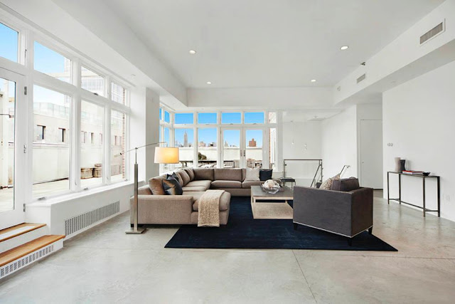 Modern living room in a NYC Penthouse with a tan sectional sofa and navy rug