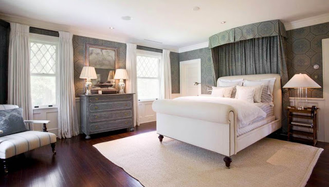 Master bedroom with fabric upholstered walls and a sleigh bed, rustic chest of drawers and night stand and a dark wood floor