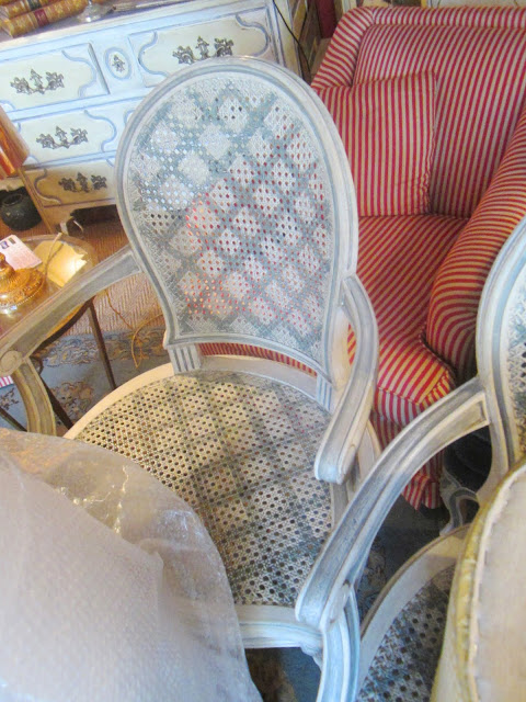 Close up of the grey painted trellis pattern on a white cane back armchairs