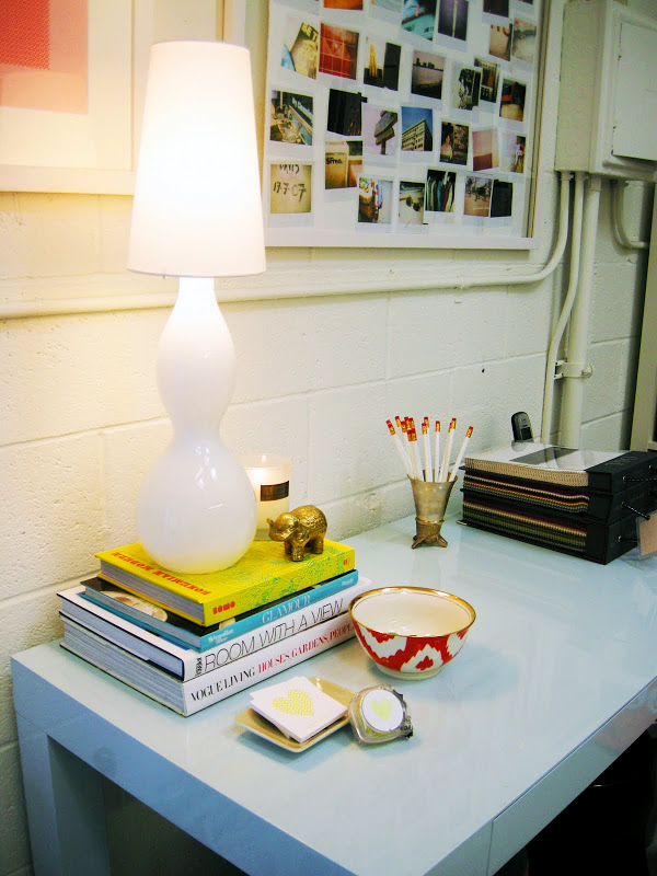 Close up of the lamp, books, card holder and ikat bowl on the light blue glossy Parsons Desk in the office