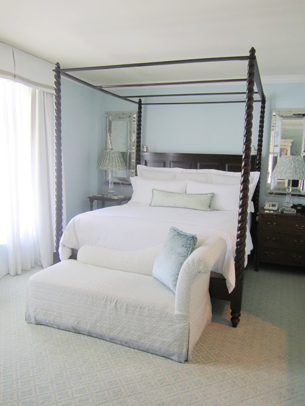 Bed in a Casa del Mar guest room with canopy bed, light blue walls, chest of drawers, mercury mirrors and chaise lounge at the foot of the bed