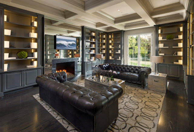 library built in bookshelves coffered ceiling brown leather tufted sofa fireplace dark wood floor