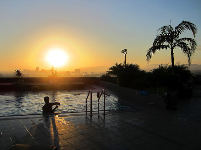 sunset over a pool with a view of Los Angeles