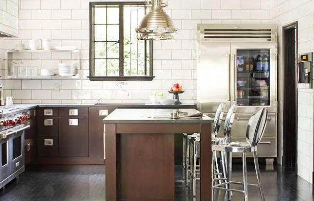 Kitchen with subway tiles walls,dark brown wood lower cabinets with matching island, stainless appliances and metal pendant lights