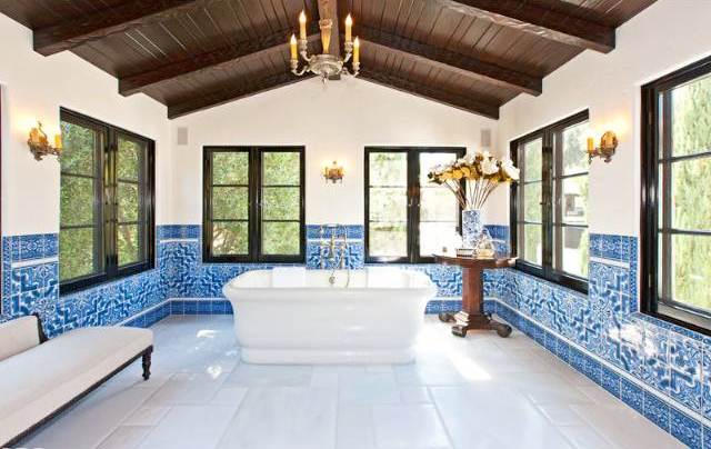 Blue and white tiled bathroom with wooden ceiling with visible beams, a chandelier and stand alone bath tub