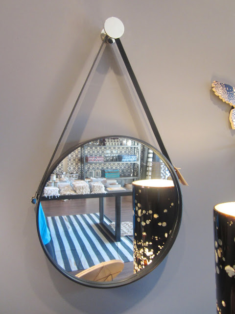 round decorative wall mirror with a leather strap