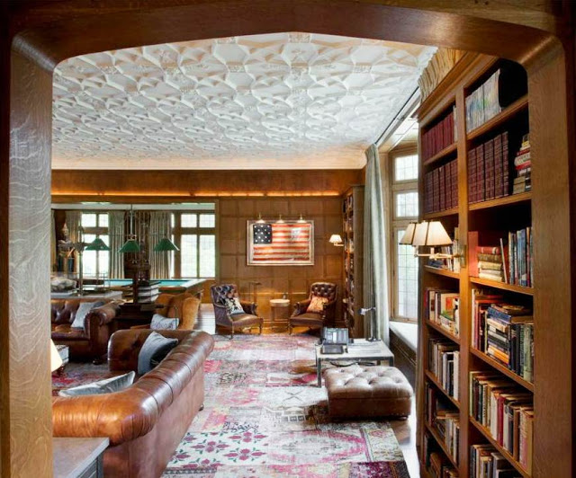 mansion with wood paneled library, built in bookshelves, brown leather sofas and chairs and a decorative ceiling