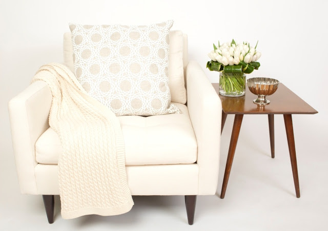 COCOCOZY Pillow on a white armchair with a cable knit throw and a wooden side table