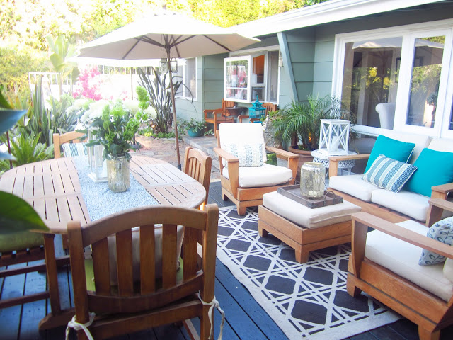 Deck with umbrella, wooden outdoor dining table and seating area with armchairs, bench and small ottoman style table