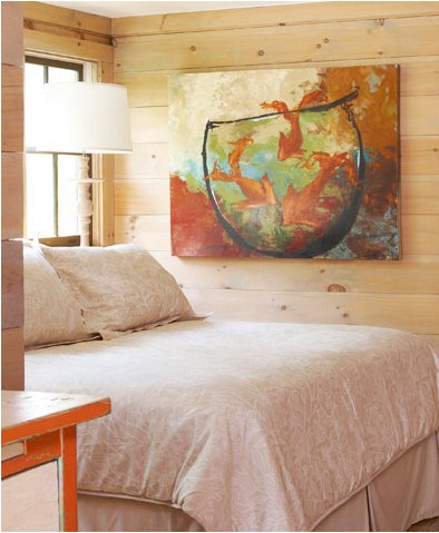Cozy bedroom with knotty light colored wood paneled walls with a large piece of modern art depicting three fish in a fishbowl