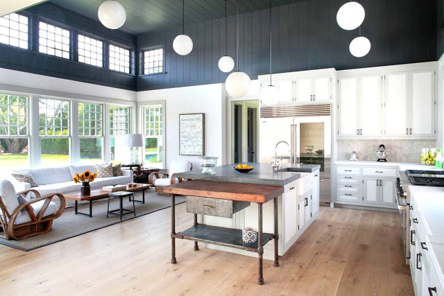 Farmhouse style kitchen with grey and white color blocked walls, pine wood floors, rattan furniture and white pendant lights