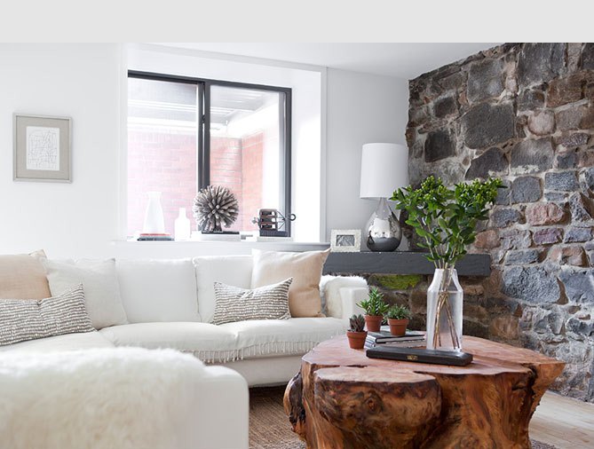 Den with a rock wall, white sofa, silver lamp, and a tree trunk coffee table