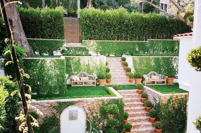 Brick stairs run through the tiered garden and lead to double carved garden doors