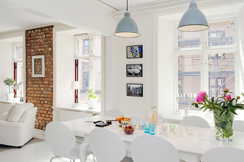 Dining room with blue pendant lights, large windows, white table and chairs