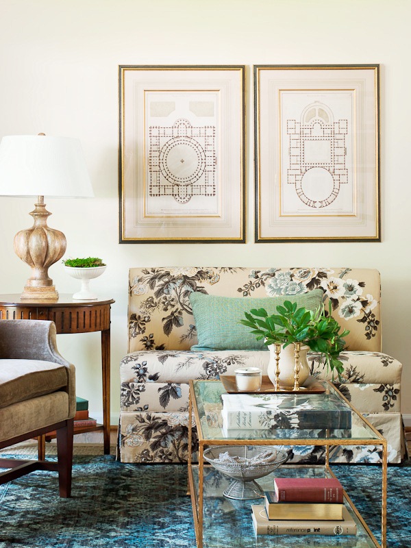 Living room with settee covered in the Schumacher Hollyhock chintz print, a glass coffee table and a blue patterned area rug