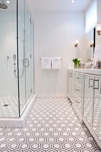 Bathroom in NYC with black and white penny round mosaic tiles used to make a hexagon pattern on the floor, mirrored cabinet doors and grey and white striped wallpaper