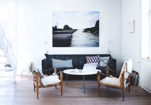 Bright living room in Copenhagen with a black sofa and leather chairs