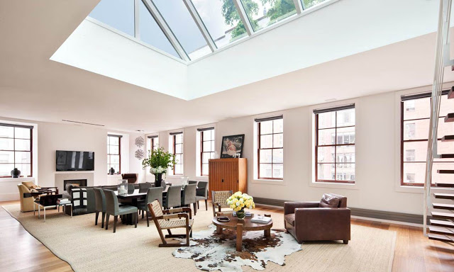open plan living room in a NYC penthouse with a massive skylight, wood floors and windows