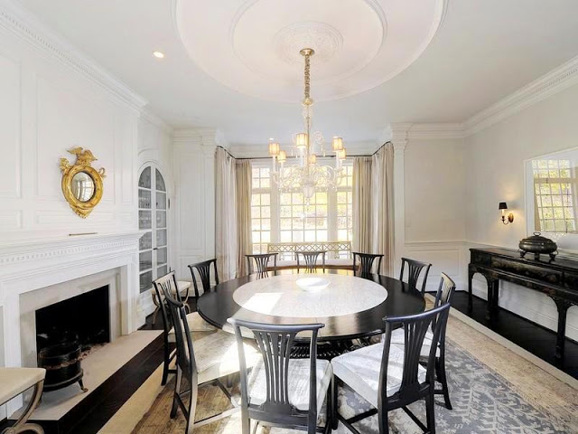 Formal dining room features a fireplace, a grand ceiling medallion and a round dark wood dining table that seats 10