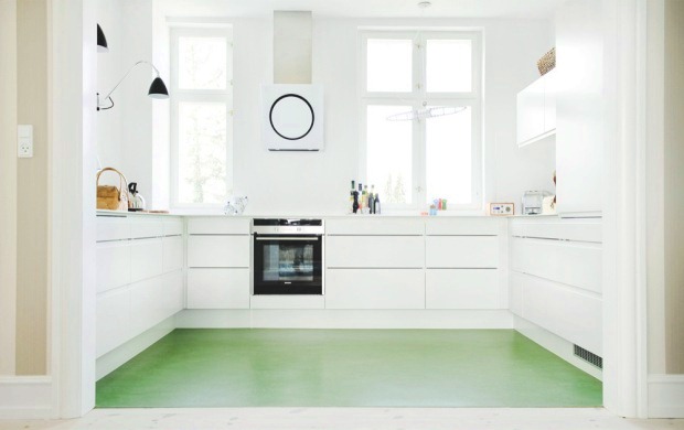 small white kitchen with green linoleum floor and black appliances