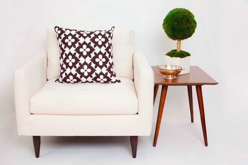 COCOCOZY Cotton Collection pillow in Coco's Flower on a white armchair next to a wood side table with a small topiary