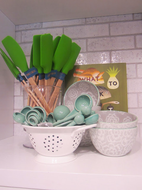 Close up of mint measuring spoons, green spatula and grey ceramic bowls with white flowers